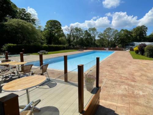 een zwembad met een tafel en stoelen op een terras bij Cosy Hideaway Lodge in Glan Gwna in Caeathro