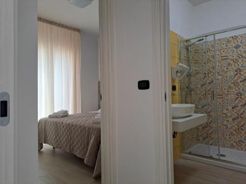 a bedroom with a bed and a bathroom with a sink at Maresol Residence in Bagnara Calabra