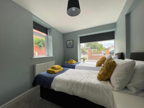 ein Schlafzimmer mit 2 Betten und gelben Handtüchern darauf in der Unterkunft Silk Apartments Spondon in Derby