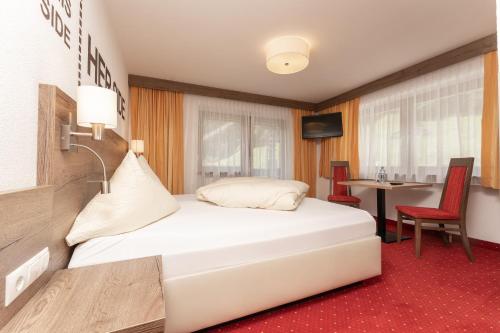 a hotel room with a white bed and a table at Alpenliebe in Sölden