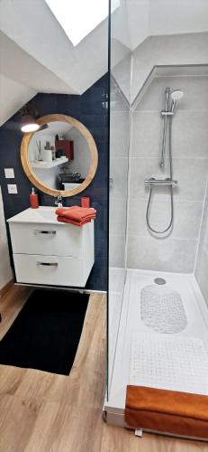 une salle de bain avec une douche avec un lavabo et un miroir dans l'établissement Bleu - Éden - appartement moderne en hypercentre, à Vichy