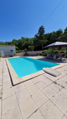 a swimming pool in a yard with an umbrella at Maison l’Eucalyptus in Chauzon