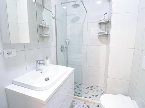 a white bathroom with a sink and a shower at Modern Apt in Mangalem21 Complex WiFi,AC in Tirana