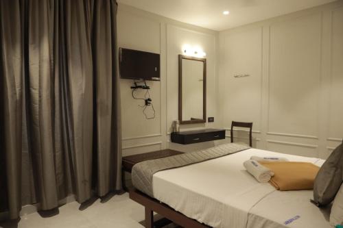 a bedroom with a bed and a mirror and a television at ARUNACHALA INN in Kanyakumari