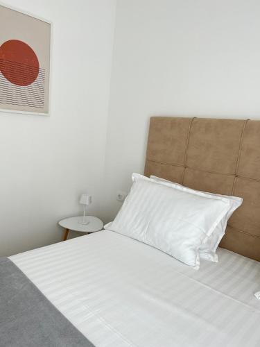 a white bed with a brown headboard and a white pillow at Aurus 2 in Korčula