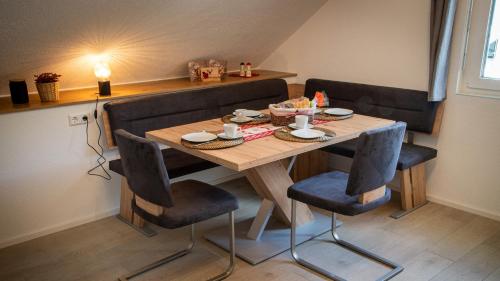 une table en bois avec deux chaises et une table avec de la nourriture. dans l'établissement Ferienwohnung Mayer, à Schluchsee
