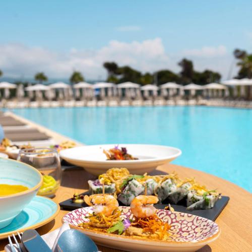 a table with plates of food next to a pool at Radisson Blu Resort Al Hoceima in Al Hoceïma