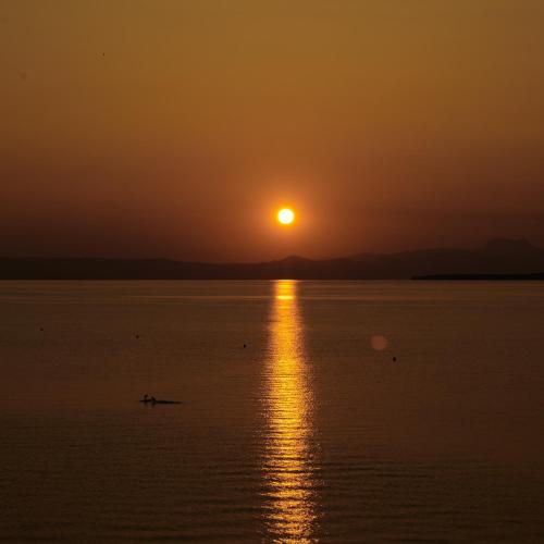 a person kayaking in the water at sunset at Hôtel de la Plage in Excénevex