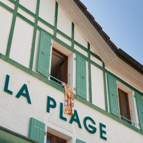 a building with green windows and a flag on the side at Hôtel de la Plage in Excénevex
