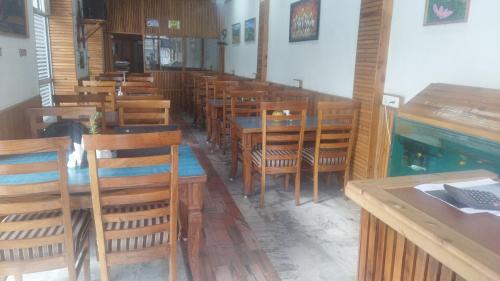 an empty restaurant with wooden tables and chairs at Hotel CM Palace - Pure Vegetarian in Ner Chowk
