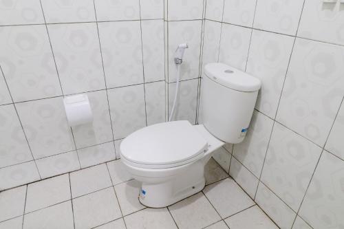 a white toilet in a white tiled bathroom at Nurudin House in Borobudur