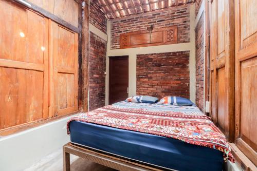 a bed in a room with a brick wall at Nurudin House in Borobudur