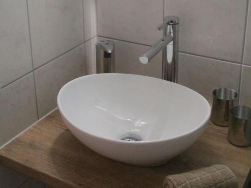 lavabo blanco sentado en una encimera de madera en el baño en Ferienwohnung am Sulzbach en Sulzburg