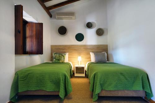 Vale Fuzeiros Nature Guest House في Vale Fuzeiros: سريرين في غرفة مع شراشف خضراء