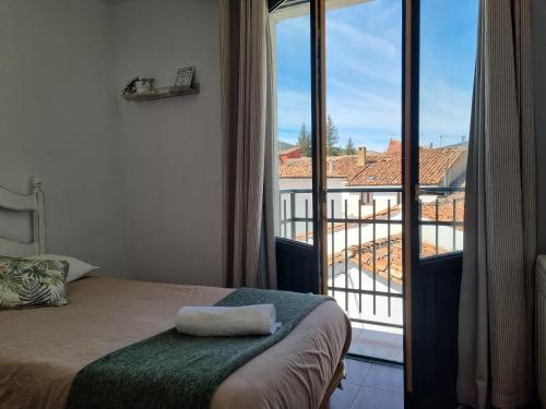 a bedroom with a bed and a view of a balcony at NcantadaROOMS in Tragacete