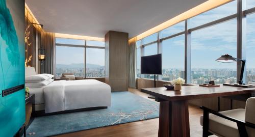 a hotel room with a bed and a desk and windows at Park Hyatt Hangzhou in Hangzhou