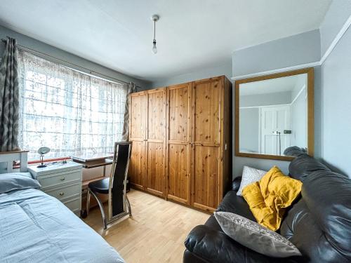 Spacious Double Bedroom in Shooters Hill في لندن: غرفة نوم مع أريكة ومكتب ومرآة