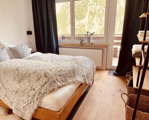 a bedroom with a bed with a white blanket and a window at Appartment Alpenrose in Saas-Fee