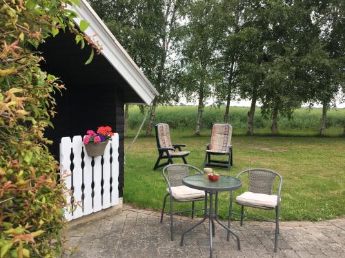una mesa y sillas en un patio trasero con una valla blanca en Stunning Romantic Cabin close to Baltic see, en Idestrup