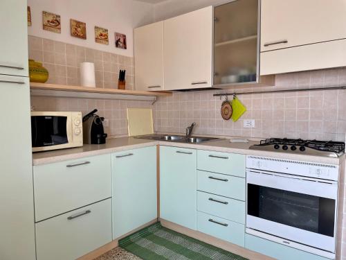 a kitchen with white cabinets and a sink and a microwave at Apartment Vista Lake Torri in Torri del Benaco