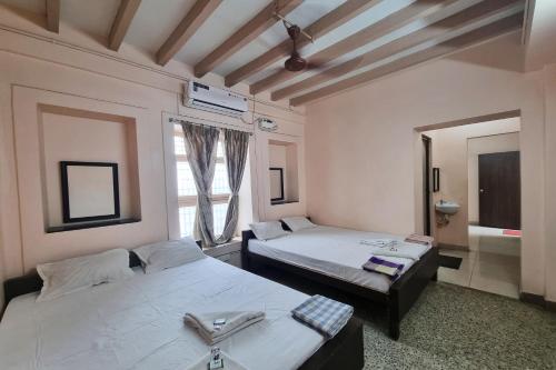 Habitación con 2 camas y espejo. en SOWMYA LODGE, en Tiruchchirāppalli