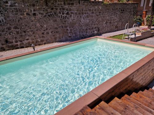a large swimming pool with a brick wall at Fidanza House in Bagnoregio