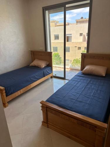 two beds in a room with a large window at Les perles de mimosa Mohammédia in Mohammedia
