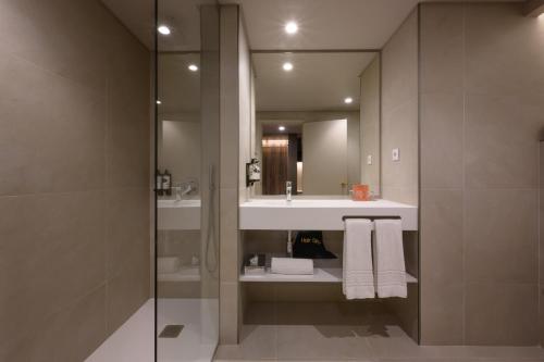 La salle de bains est pourvue d'un lavabo et d'un miroir. dans l'établissement Hotel Coimbra Aeminium, Affiliated by Meliá, à Coimbra