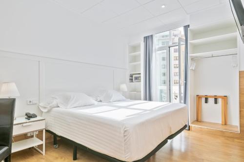 een witte slaapkamer met een bed, een bureau en een raam bij Venecia Plaza Centro in Valencia