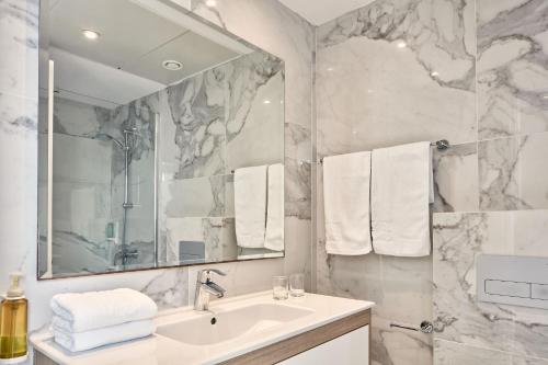 a white bathroom with a sink and a mirror at Atlantica Sancta Napa Hotel in Ayia Napa