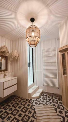 La salle de bains est pourvue d'un lavabo et d'un lustre. dans l'établissement Maison Hortense 4 étoiles piscine chauffée et sauna, à Buxeuil