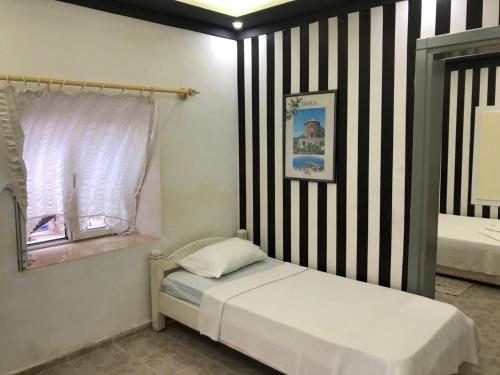 a small bedroom with a bed and a striped wall at HALİSE APART in Emecik