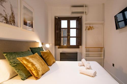 a bedroom with a white bed with gold pillows at Granadi Apartamentos in Granada