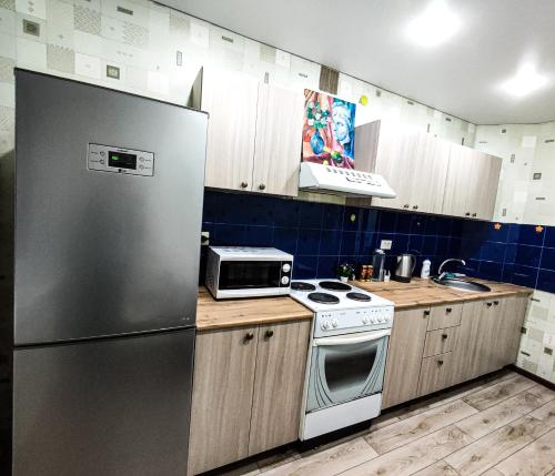 uma cozinha com um frigorífico de aço inoxidável e armários de madeira em Уютная трёхкомнатная квартира em Pavlodar