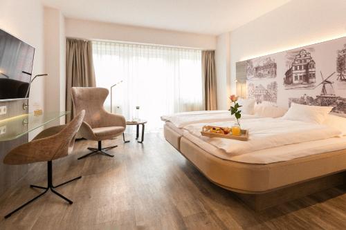 een slaapkamer met een bed, een bureau en een stoel bij Hotel Deutsches Haus in Gifhorn