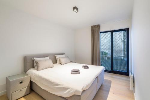 - une chambre blanche avec un grand lit et une fenêtre dans l'établissement Modern appartement in hartje Oostende, à Ostende