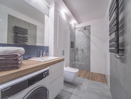 a white bathroom with a washing machine in it at Szmaragdowy Spichlerz Apartament in Gdańsk