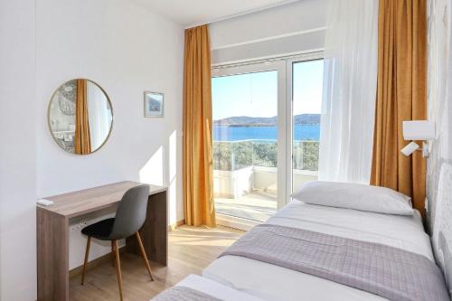 a hotel room with a bed and a desk and a window at Villa Capan ZadarVillas in Sveti Filip i Jakov