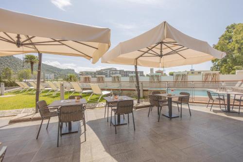 a patio with tables and umbrellas and a pool at Novotel Salerno Est Arechi in Salerno