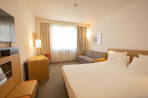 a hotel room with a bed and a couch at Novotel Salerno Est Arechi in Salerno