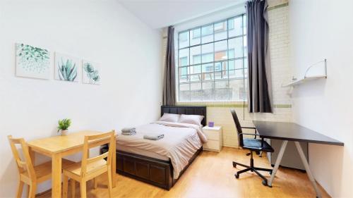 Amazing Studio Apartment في لندن: غرفة نوم بسرير ومكتب وطاولة