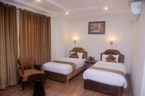 a hotel room with two beds and a chair at The Rich Hotel & Apartments in Lahore