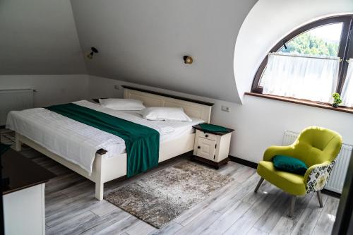 um quarto com uma cama, uma cadeira e uma janela em Casa Românească em Putna