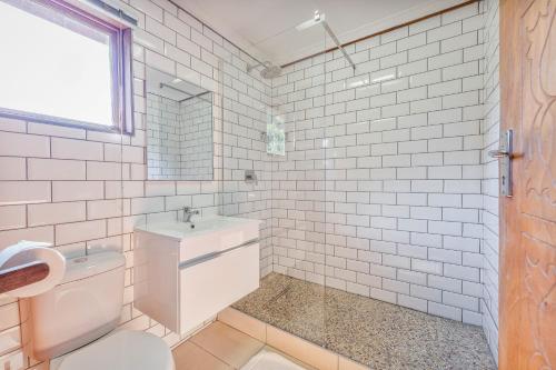 a white tiled bathroom with a toilet and a sink at Sunset Lodge in St Lucia