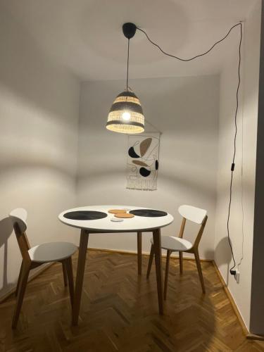 a table and chairs in a room with a light fixture at Klimatyczna kawalerka w centrum in Gdynia