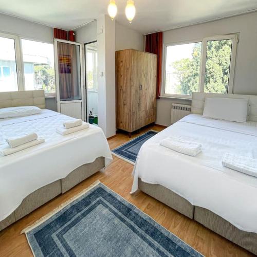 two beds in a bedroom with two windows at Sweet Flat For Sweet Famılies in Istanbul