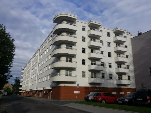 biały apartamentowiec z balkonami przy ulicy w obiekcie Apartamenty Słupsk w mieście Słupsk