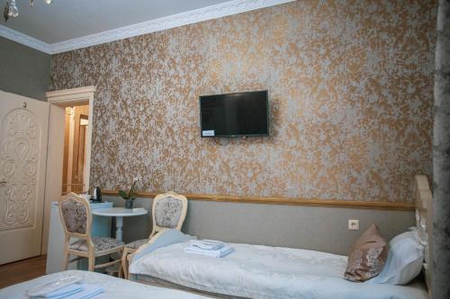a hotel room with two beds and a tv on the wall at Borjomi Classic Hotel in Borjomi