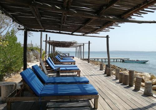 a row of blue beach chairs on a wooden deck at Centro Ubuntu in Isla Grande