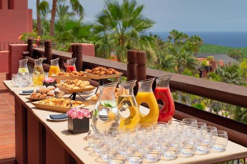 a table with food and wine glasses on a balcony at The Ritz-Carlton Tenerife, Abama in Guía de Isora